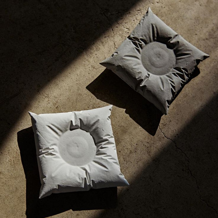 A pair of handmade white pillow-shaped candle holders in warm sunlight