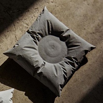 A white pillow-shaped candle holder with hand-formed folds